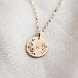 Round initial floral pendant necklace with small engraved letter M on gold chain
