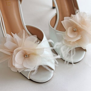 Ivory flower shoe clips with pearl centers on white bridal shoes