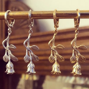 Rose-stem huggie hoop earrings with dangling rose charms, gold-tone and silver-tone