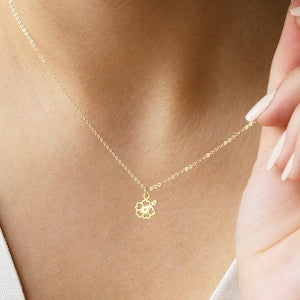 Delicate gold-tone necklace with small hibiscus flower charm on a fine chain