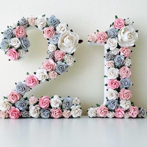 Floral number decoration made of faux roses in pink, blue, and white on a light base