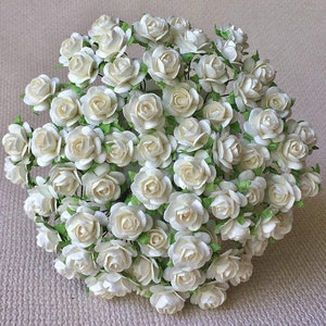 Set of mini white paper flowers with small green leaf accents for DIY crafts