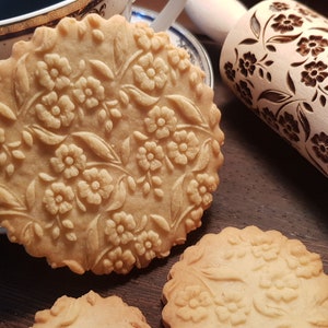 Handmade wooden rolling pin with floral engraved embossing pattern, end view