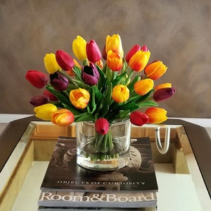 Faux tulip centerpiece in a clear glass jar with yellow, red, and pink blooms