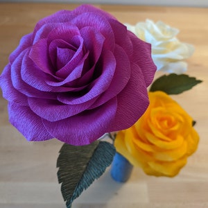 Purple crepe paper rose craft with layered petals and green leaf detail