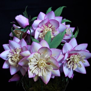 Purple paper flower bouquet with green leaves, layered petals and center stamens