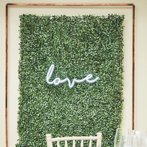 Green artificial foliage wall tile backdrop with white love lettering