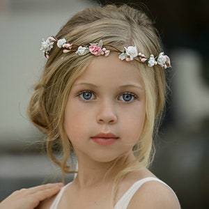 Blush pink flower crown with small white blossoms on a child’s head