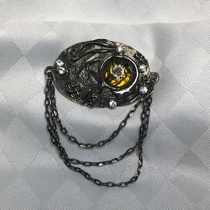 Abstract resin flower brooch with dark filigree, round yellow rhinestone center, dangling chains