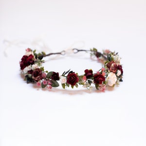 Burgundy flower hair crown with small white accents and green foliage