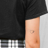Minimalist heart and flower temporary tattoo on forearm, fine line black ink