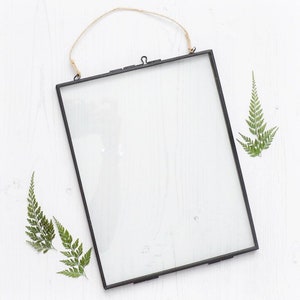 Black wall photo frame with clear front and hanging loop, blank display surface