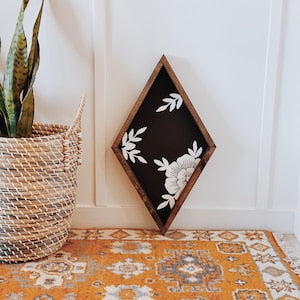 Diamond wooden wall sign with dark center and white floral leaf motif