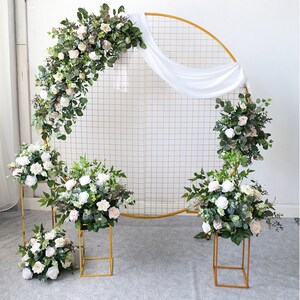 White and blush flower greenery garland on round gold arch with white drape