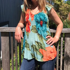 Floral summer top with turquoise base, sleeveless drape and orange/red flower print
