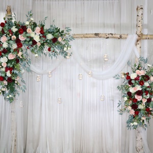 Floral corner swag for wedding arch with pink and burgundy blooms and greenery, with lights