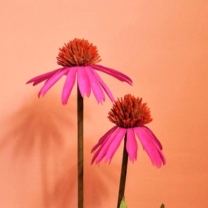 Pink cone-shaped paper flowers with dark orange centers on stems