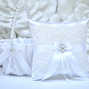 White ring bearer pillow with lace trim, pearl-like center, and satin bows