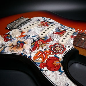Decorative guitar pickguard with colorful folk floral and heart graphic on sunburst guitar