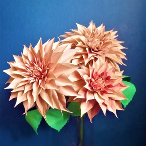 Peach paper dahlia flower with layered petals and green leaf accents