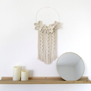 Off-white macrame wall hanging tapestry with floral motifs and long fringe tassels