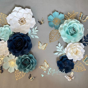 Paper flower wall decor with white, teal, and dark blue blooms and small butterflies