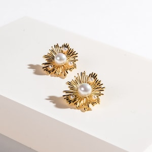 Gold-tone sunburst pearl stud earrings with round white pearl centers