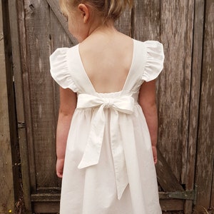 White baby dress with ruffled cap sleeves and tied bow at the back