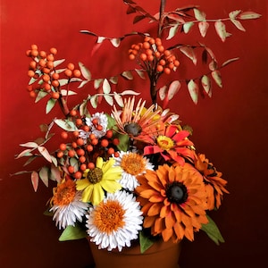 Paper flower arrangement with orange and white blooms, red berries, and green leaves
