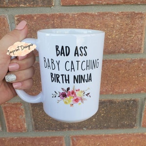 White ceramic mug with bold black text and small floral graphic on front