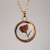 Rose glass locket necklace with pressed flower inside circular pendant and gold chain