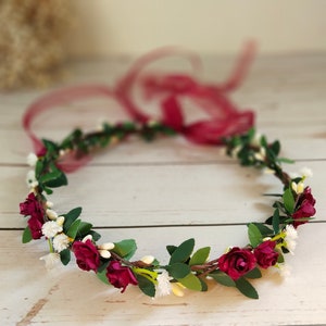 Burgundy flower crown headband with green leaves and small white blooms