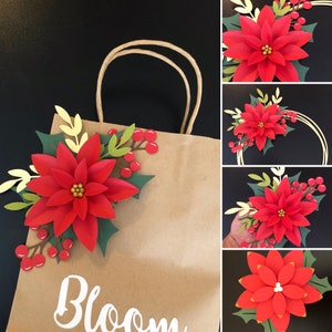 Brown gift bag with red poinsettia paper flower and green leaves, holding arched handles