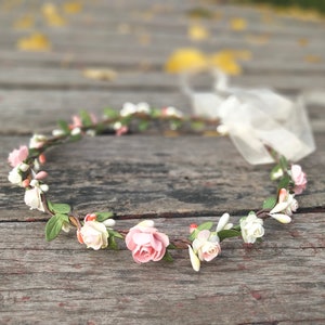 Girl's floral flower crown with pink and white blossoms, green leaves, and flexible wreath