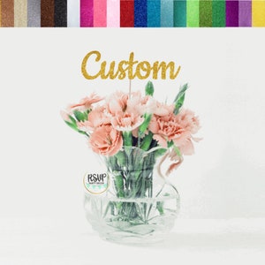 Centerpiece topper with cursive 'Custom' above a pink flower bouquet in glass vase