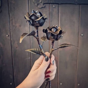 Handheld forged steel rose with twisted metal petals and leaves, dark finish