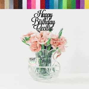 Happy Birthday centerpiece topper with black cursive text in a clear vase with pink flowers