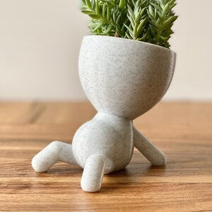 Speckled gray ceramic people planter with three legs holding a small succulent
