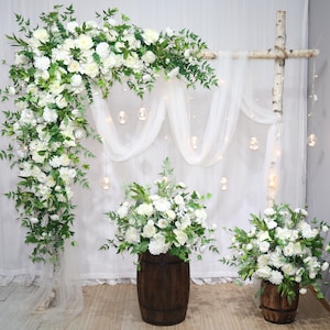 Wedding archway floral garland with white flowers, green foliage, and draped white fabric