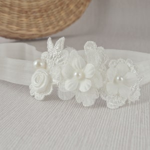 Off-white lace baby headband with three fabric flowers and pearl accents