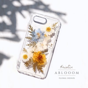 Clear phone case with pressed wildflowers in blue, yellow, and white