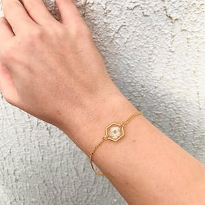Gold pressed flower bracelet with small hexagonal charm on a thin chain