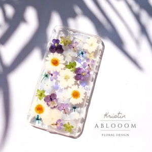 Clear pressed flower phone case with purple, yellow, and white floral design