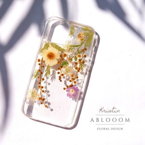 Clear pressed-flower phone case with dried blossoms and gold flecks