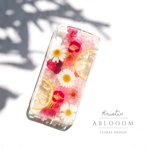 Transparent pressed-flower phone case with pink red blooms and citrus slice accents