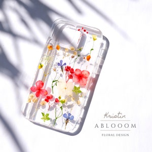 Clear pressed-flower phone case with colorful blooms on transparent back
