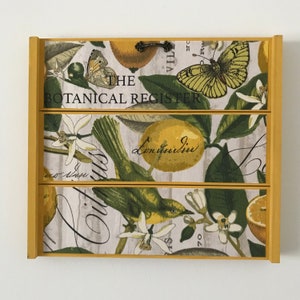 Framed botanical wall art with green leaves and butterflies in a light background