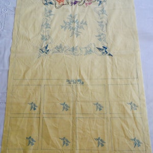 Yellow tablecloth fabric with blue embroidered service motifs and grid layout