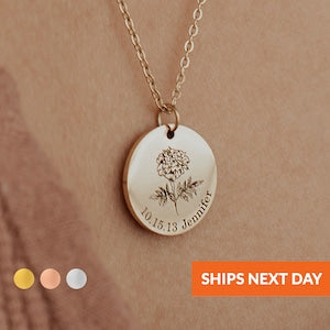 Round gold birth flower necklace pendant with small engraved name and date on a chain