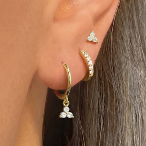 Gold huggie hoop earrings with small white flower charms on a hoop
